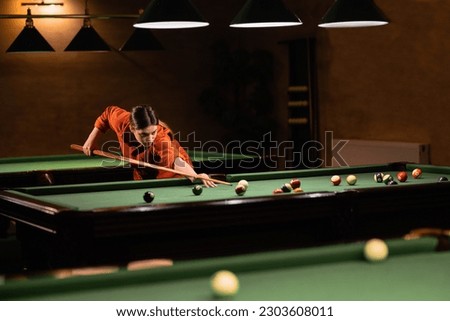 Sports game of billiards on a green cloth. Woman playing with Multi-colored billiard balls and cue on a pool table. Billiard sports concept. Royalty-Free Stock Photo #2303608011