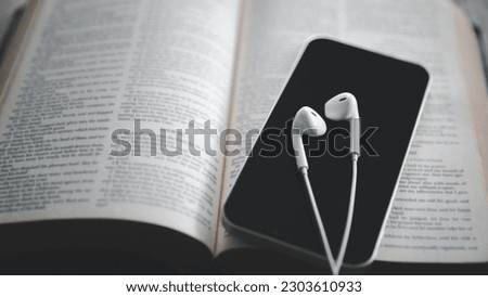 Christian online technology concept. Earphones over the holy bible with digital smartphone, Online live church for sunday service. Holy bible book and online study.