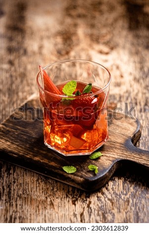 Homemade compote of rhubarb and strawberries on wooden table with mint in glass-rustic background.