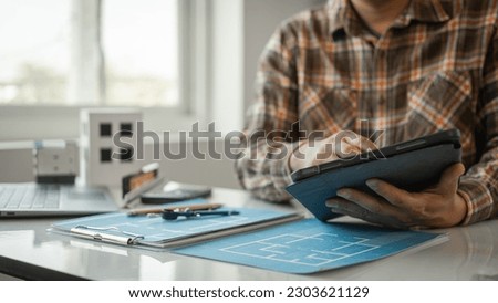Architecture Interior designer working with building apartment plans blueprints on desk table at construction site office, closeup.