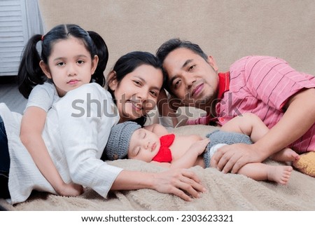 Happy Asian family taking pictures together. Parents, eldest daughter and youngest son Spend time together on a family day. Mother, father and adorable children smile and look at the camera.