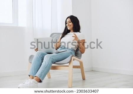 Woman relaxing at home sitting in a chair with a laptop, lifestyle home mood. Mockup, free copy space