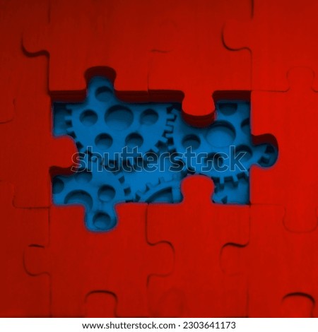 solving the problem concept - red puzzles and blue cogwheels. wooden gears under the puzzle, the concept of moving to the next level. Cog wheels coming out from underneath a jigsaw puzzle.