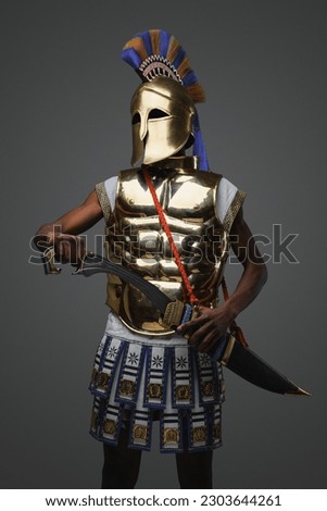 Shot of black greek warlord with golden armor against gray background.