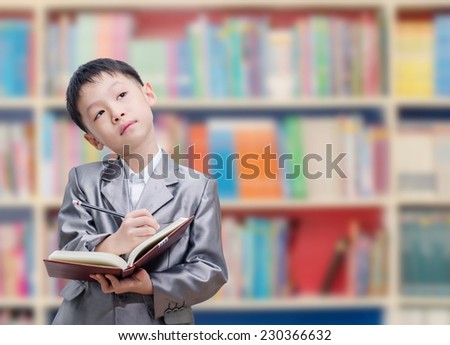 Asian boy reading book in school library