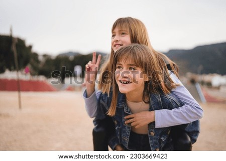 Girl on top of girl taking a picture in the park. Sisters having fun together. Winter vacation and concept of friendship.