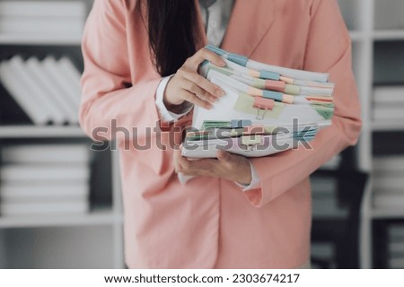 Young professional businesswoman working with stack of papers, searshing for the right file to work with.