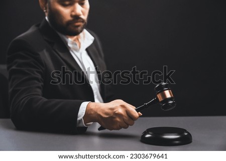 Focus wooden gavel hammer with burred lawyer in black suit holding gavel in background on his desk, symbol of legal justice and integrity, balanced and ethical decision in court of law equility