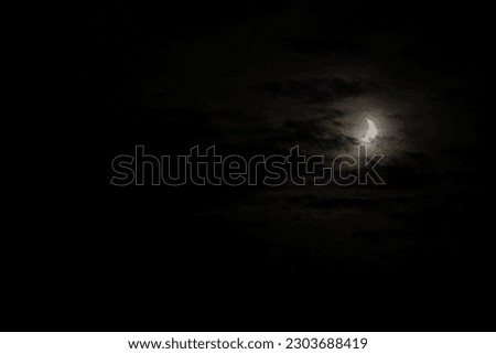 A narrow semicircle of the moon in cloudy cloudy weather. Sickle, crescent moon at dusk to overlay on your photos. Natural evening background