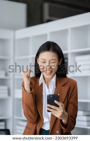 Happy Asian woman holding a smartphone, happy smiling, getting bonus money.