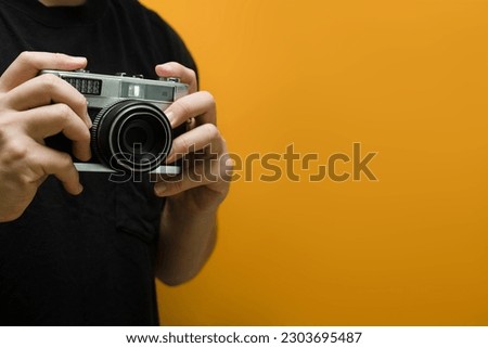 Man hands holding retro photo camera on yellow background with copy space