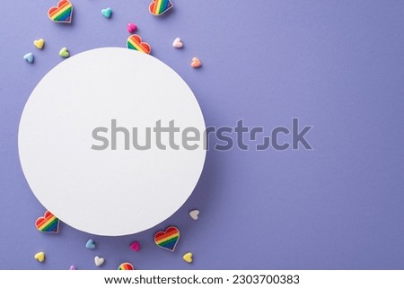 The essence of an LGBT festival is beautifully represented in this top view flat lay of symbolic accessories, including badges, hearts, against a striking violet backdrop with empty circle for text