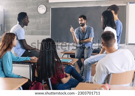 Teenager students and young male teacher sharing group discussion at School - Youth counselor advisor Royalty-Free Stock Photo #2303701711
