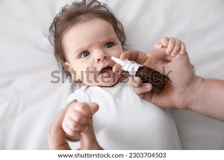 Father taking care of little baby suffering from runny nose in bed, top view Royalty-Free Stock Photo #2303704503