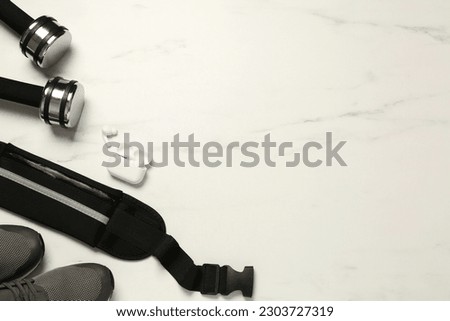 Flat lay composition with black waist bag on white marble table, space for text Royalty-Free Stock Photo #2303727319