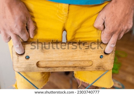 strong male rock climber's hand holds board for finger strength training with one finger. climbing workout at home. rock climber's hand close-up. fingerboard and hangboard
