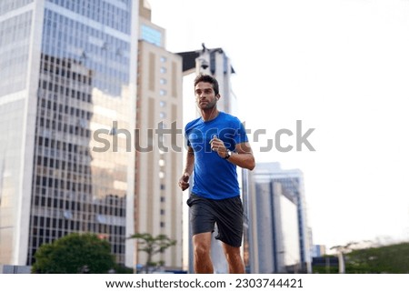 Sports, exercise and man running in the city for health, wellness or training for a marathon. Fitness, runner and male athlete doing an outdoor cardio workout for endurance or speed in an urban town. Royalty-Free Stock Photo #2303744421