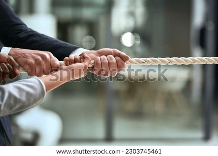 Hands, teamwork and rope with business people pulling during a game of tug of war in the office. Collaboration, help and strength with a team of employees or colleagues holding onto an opportunity Royalty-Free Stock Photo #2303745461