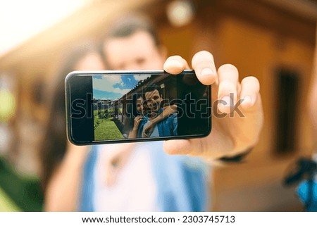 Happy couple, hug and phone screen for selfie, photo or profile picture together in relationship outdoors. Hand of man holding smartphone with woman hugging for love, memory or capture outside home