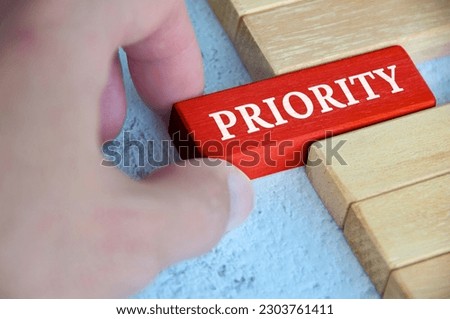 Hand placing red wooden blocks with text - Priority. Priority and business concept.