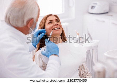 Detail of dentist applying local anesthetic to patient for numbing the pain before procedure; doctor applying lip fillers to female patient