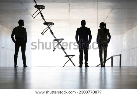 Business people standing next to office chair installation art