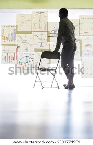 Businessman viewing charts and graphs on office wall Royalty-Free Stock Photo #2303771971