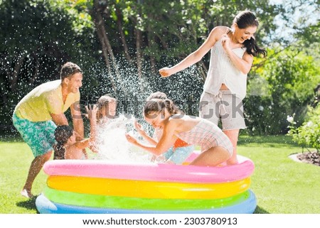 Family playing together in wading pool Royalty-Free Stock Photo #2303780913