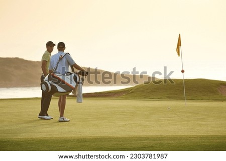 Men on golf course overlooking ocean Royalty-Free Stock Photo #2303781987