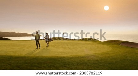 Golfer and caddy walking on golf course Royalty-Free Stock Photo #2303782119