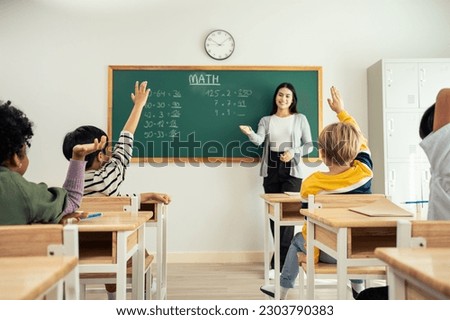 Group of student learn with teacher in classroom at elementary school. Attractive beautiful female instructor master explain and educate young children with happiness and fun activity at kindergarten. Royalty-Free Stock Photo #2303790383