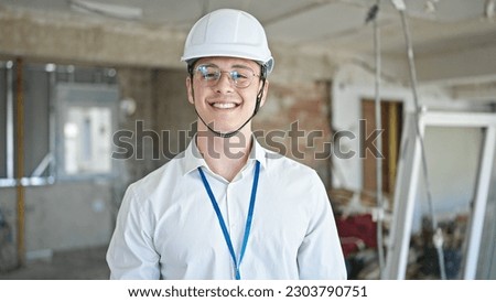 Young hispanic man architect smiling confident standing at construction site