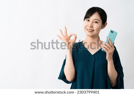 A young woman making an OK sign while holding a smartphone