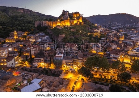 Night illumination of Tbilisi from the drone view of Narikala fortress and old town of Tbilisi, Georgia. Beautiful panoramic view of Tbilisi at sunset.