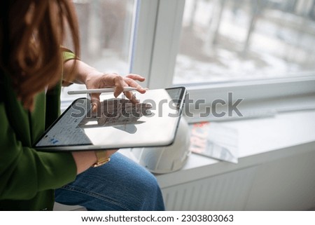 A girl in a green jacket works with a tablet