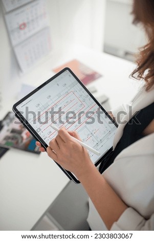 Architectural drawings on tablet. Brunette girl in a white jacket