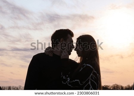 Silhouette photo of a couple in love at sunset.Portrait of a man and a woman.Photo at sunset.Silhouette portrait.Rays of the sun.Romantic photo.Backlight.Hugs of a couple in love.Sensual photo.Date. Royalty-Free Stock Photo #2303806031