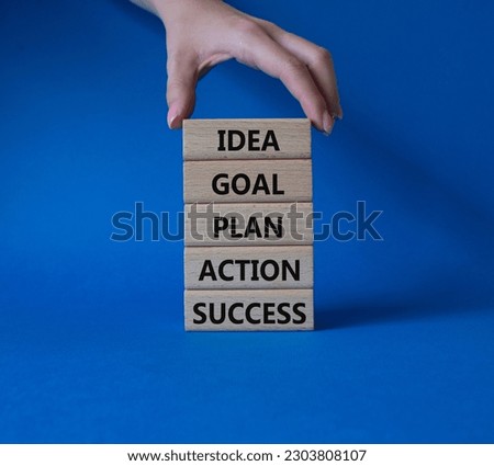 Idea Goal Plan Action Success symbol. Concept words Idea Goal Plan Action Success on wooden blocks. Beautiful blue background. Businessman hand. Business concept. Copy space.