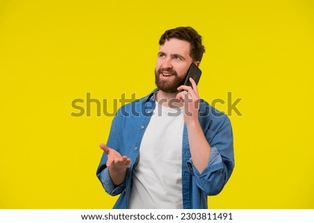 Young smiling happy cheerful caucasian man 20s wear white casual shirt talk speak on mobile cell phone conducting pleasant conversation look aside isolated on plain yellow background studio portrait.