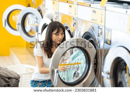 line of industrial washing machines in a public laundromat. Caucasian woman washing her clothes in automatic laundry machine Royalty-Free Stock Photo #2303831881