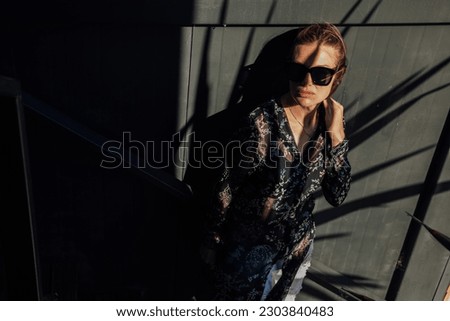fashionable woman stands in the shadows against a black wall