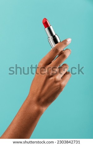 Unrecognizable African American female demonstrating bright red lipstick against turquoise background in studio