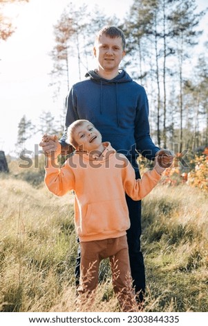 Happy father's day. Dad and son on a walk in the forest in sunny weather. Family leisure. The father holding son hands son and smiles. Front view