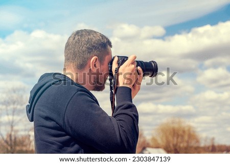 Person taking picture by reflex camera. Man with black photo camera in warm summer day Royalty-Free Stock Photo #2303847139