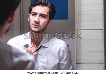Aggressive businessman standing angry in front of mirror in the restroom after exhausting busy workday Royalty-Free Stock Photo #2303861233