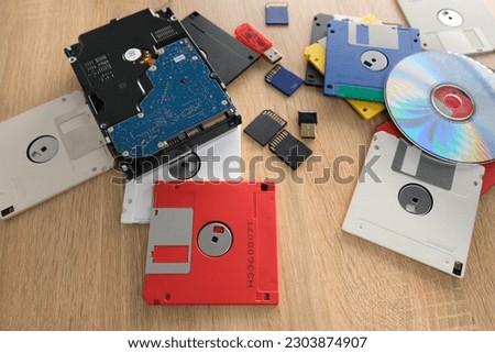 vintage retro electronic data storage, External memory in Computer Organization, devices from 80s, 90s, cd disk, flash drives, modern hard disk scattered on table. Stack floppy disks, selective focus