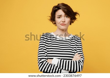 Young sad grumpy frustrated dissatisfied displeased woman wearing casual striped black and white shirt look camera hold hands crossed folded isolated on plain yellow color background studio portrait Royalty-Free Stock Photo #2303876497