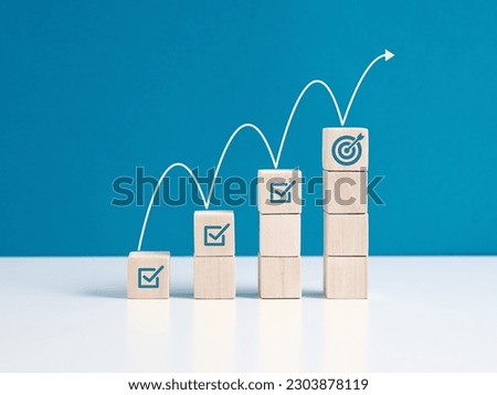 Steps for goal achievement and business success. Project tracking and task completion. Managing project timeline. Checkmark and target goal  symbols on wooden cubes. Royalty-Free Stock Photo #2303878119