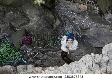 rock climber. man climbing back. traditional crag climber. cliff in the woods. climber on a natural cliff in a rough environment. smiling woman climbing. happy climber smiling. climbing photography Royalty-Free Stock Photo #2303878343