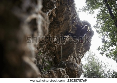 rock climber. man and woman climbing back. traditional crag climber. cliff in the woods. climber on a natural cliff in a rough environment.
